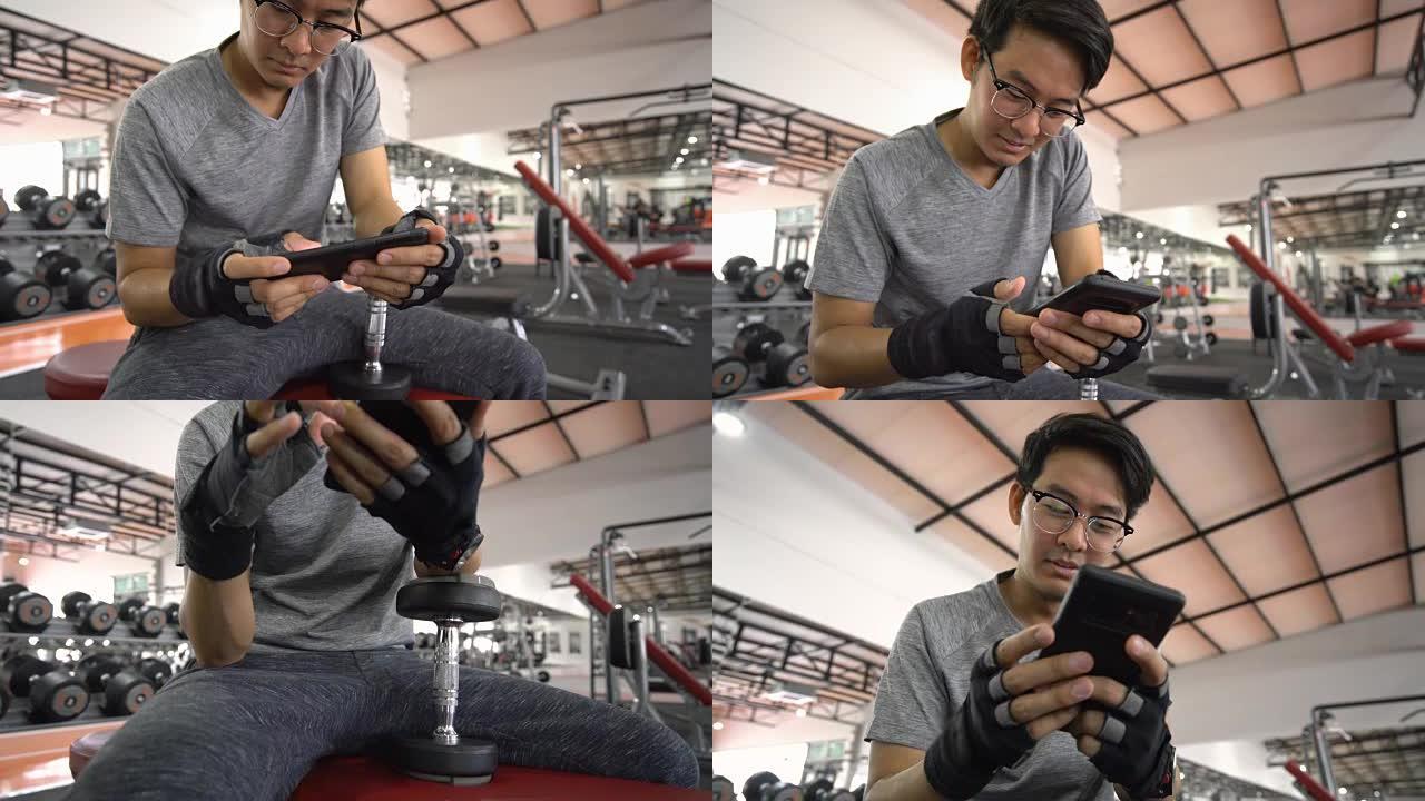 亚洲男子在密集的交叉健身健美健身房训练后，在长凳上休息时使用智能手机拍摄了2张照片