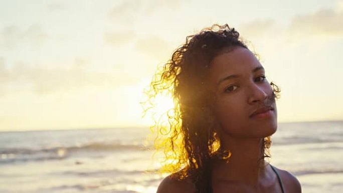 日落时海滩上美丽的年轻非洲裔美国妇女的肖像，柔和温暖的复古色调