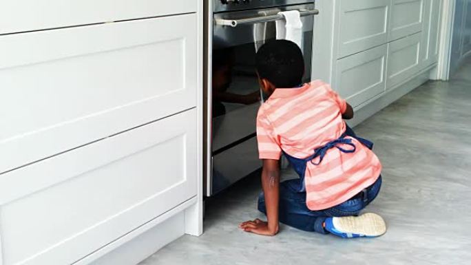 好奇的男孩在烤箱里偷看并打电话给他的父亲