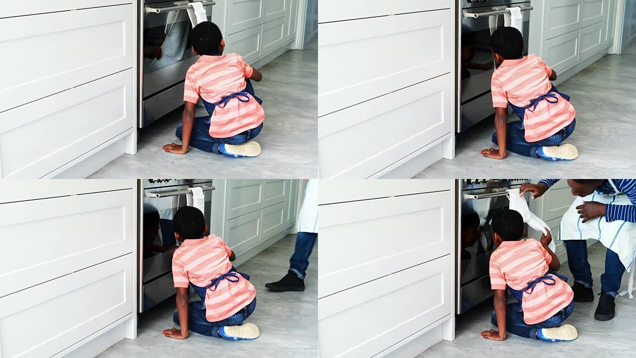 好奇的男孩在烤箱里偷看并打电话给他的父亲