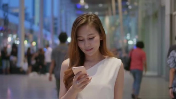女人在购物中心使用智能手机，慢动作
