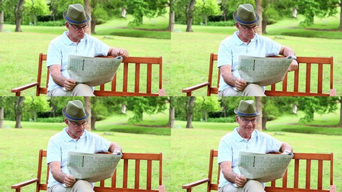 退休男子在公园长椅上阅读报纸