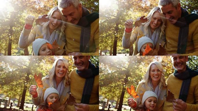 爸爸妈妈和女儿拿着树叶在户外微笑