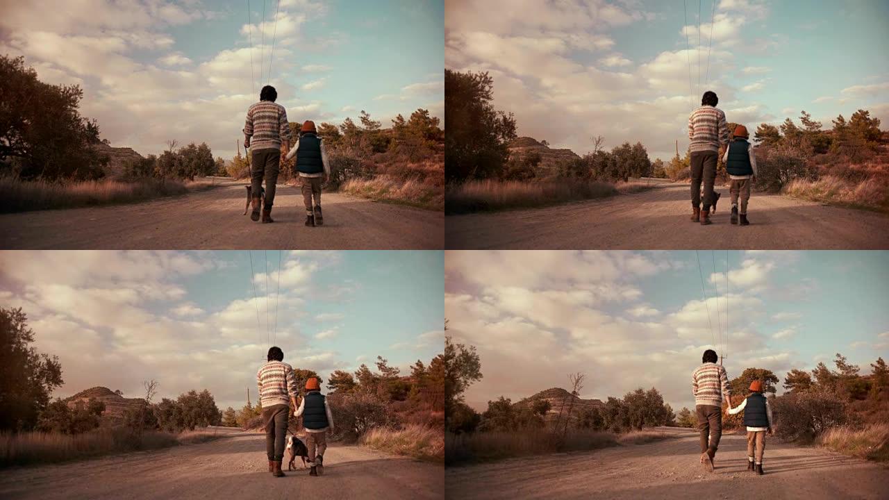 年轻的父亲和儿子在自然小径上与狗一起散步