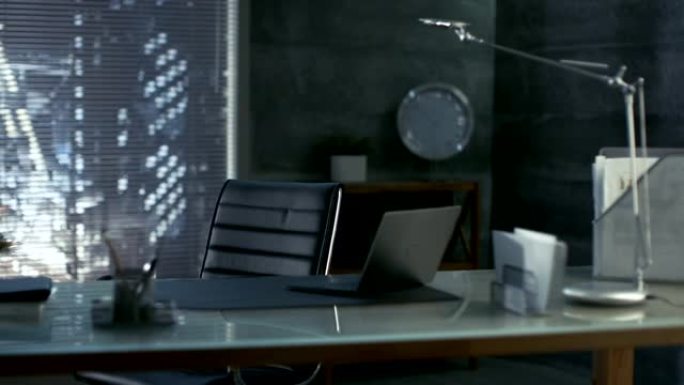 现代办公室的镜头，上面放着皮椅，木头和玻璃桌子，上面放着笔记本电脑。工作区带有深色的色彩，窗外可以看