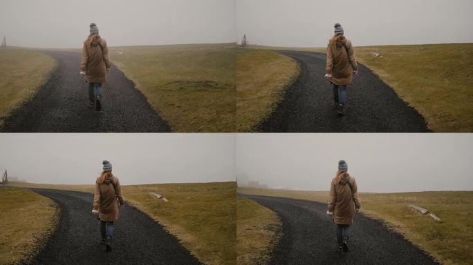 年轻女子独自走过田野的后景。探索冰岛自然的时尚女性