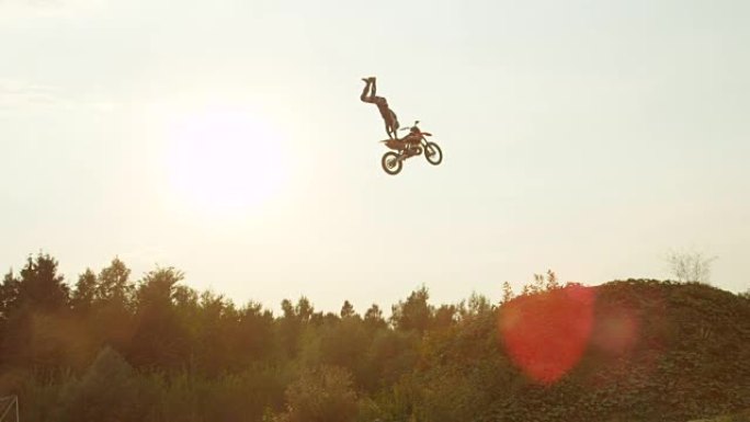 慢动作: 极端职业越野摩托车手在太阳上跳跃超人把戏