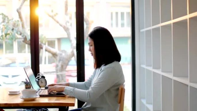 年轻女子在图书馆用笔记本电脑和热咖啡工作