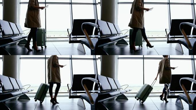 女人拿着数字平板电脑，带着行李走路