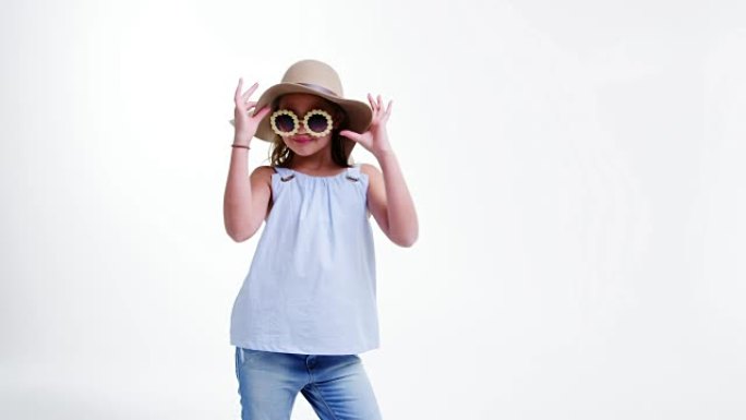 戴着帽子和太阳镜的女孩在白色背景下摆姿势