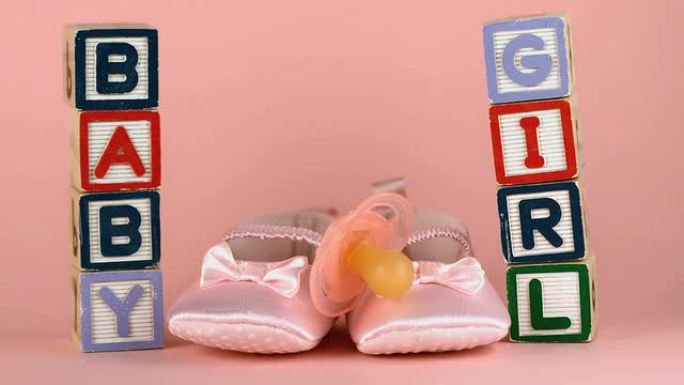 粉红色的安抚用品落在婴儿鞋和积木前