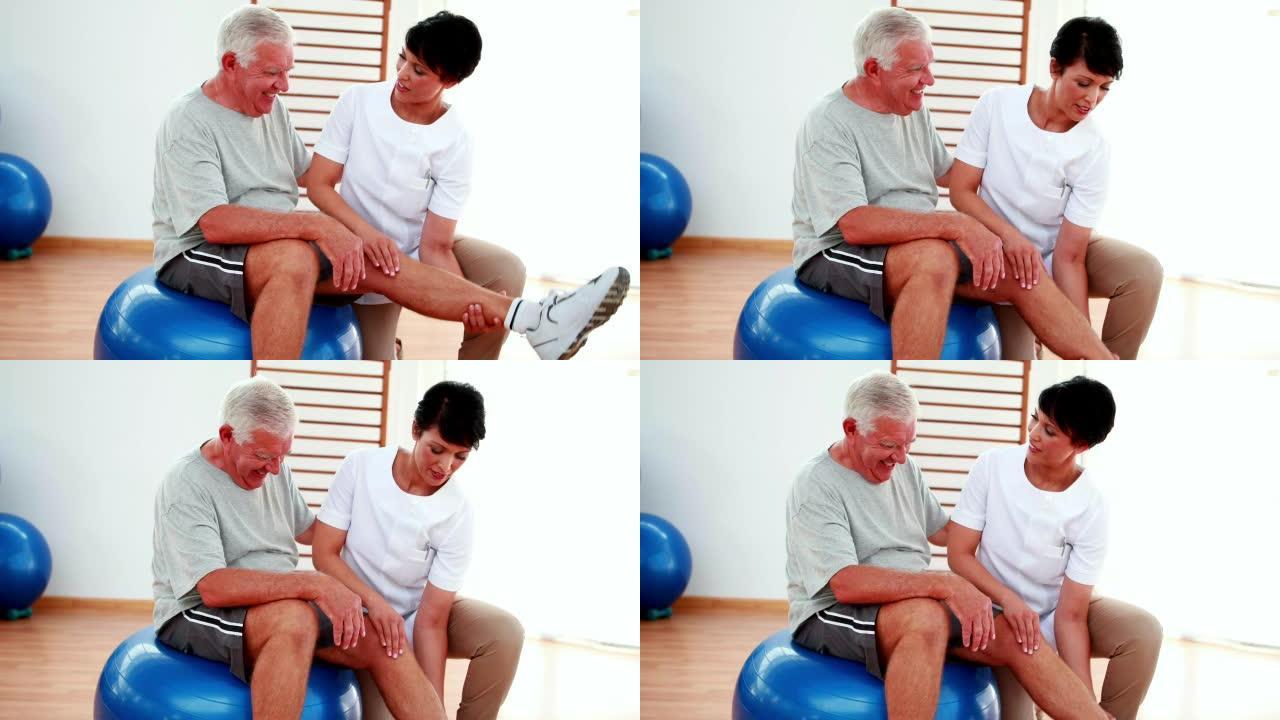 微笑的物理治疗师帮助老年患者弯曲膝盖