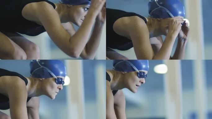 专业的集中女性游泳者在跳进水中之前在起跑器上戴着护目镜。
