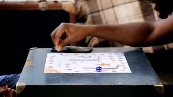 多民族夫妇玩棋盘游戏的特写镜头。男子掷骰子，在场上移动并拿走卡片