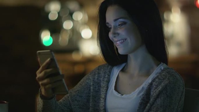 晚上使用智能手机进行视频通话，笑容灿烂的少女。休闲生活方式。