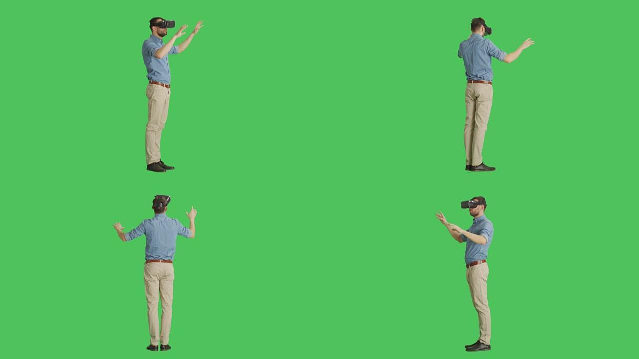 一个戴着虚拟现实眼镜的英俊男子的长镜头与外部世界互动，而相机在他周围旋转。背景是绿色屏幕。