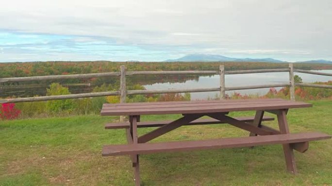 俯瞰湖泊和迷人多彩的森林的孤独野餐桌