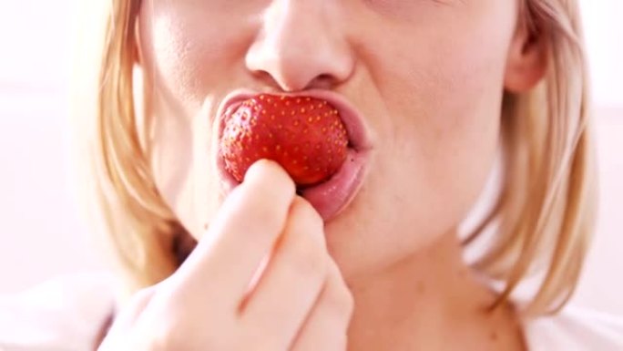 特写一个金发女人吃草莓