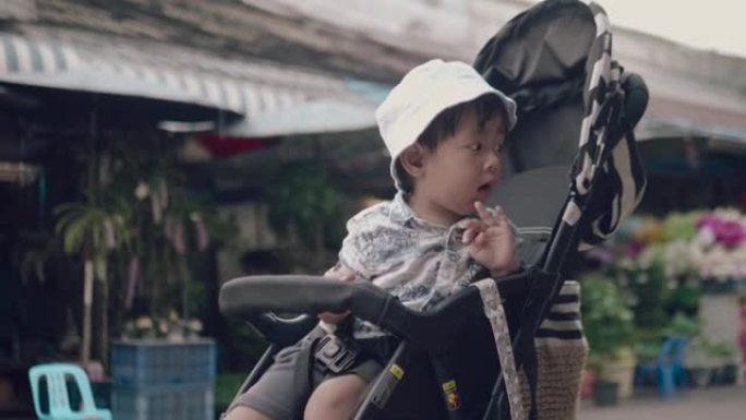 跳蚤市场婴儿车里的亚洲男婴。