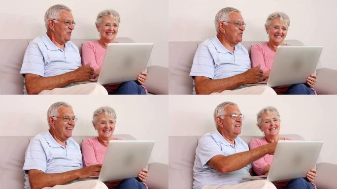 老年夫妇坐在沙发上使用笔记本电脑