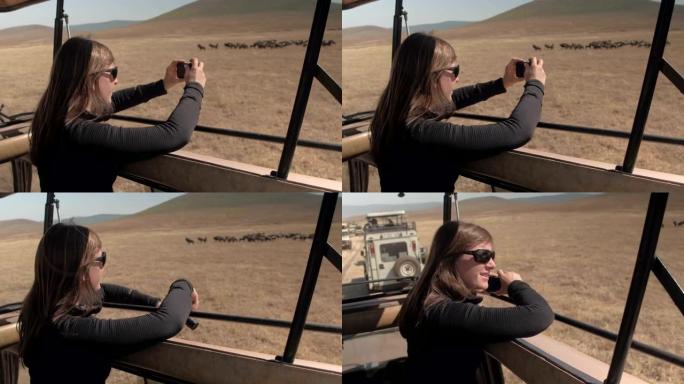 特写: 微笑的女孩在阳光明媚的非洲大草原上拍摄游戏动物的照片