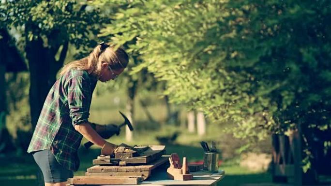 在花园里DIY。女人翻新旧木制家具