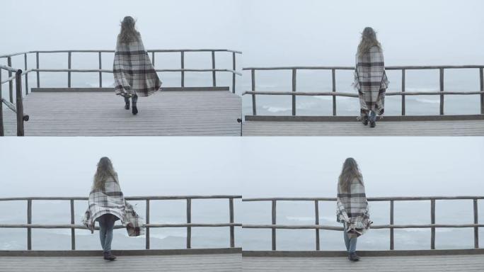 背景式的年轻女子站在木墩上眺望远方。女性在雾天独自度过