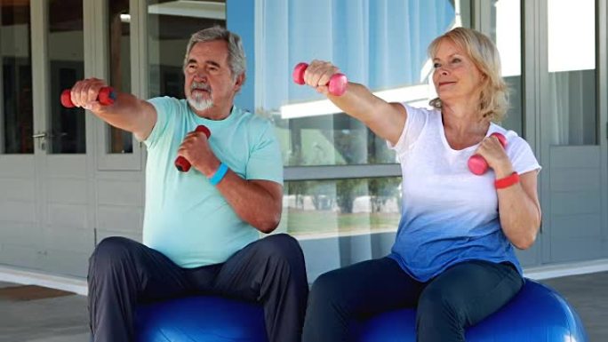 高级夫妇在健身球上用哑铃锻炼