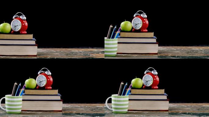 苹果和闹钟放在书架上，桌子上有彩色铅笔