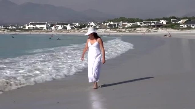 女人在海滩上沿着水线行走，南非开普敦