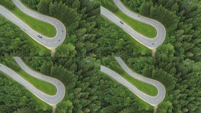 空中: 摩托车和汽车在起伏的道路上驶过发夹弯