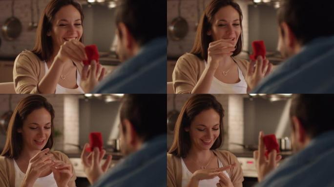 一个接受求婚的漂亮女孩的特写镜头。他为她打开了戒指盒。她拿了戒指，然后用手指试了试。