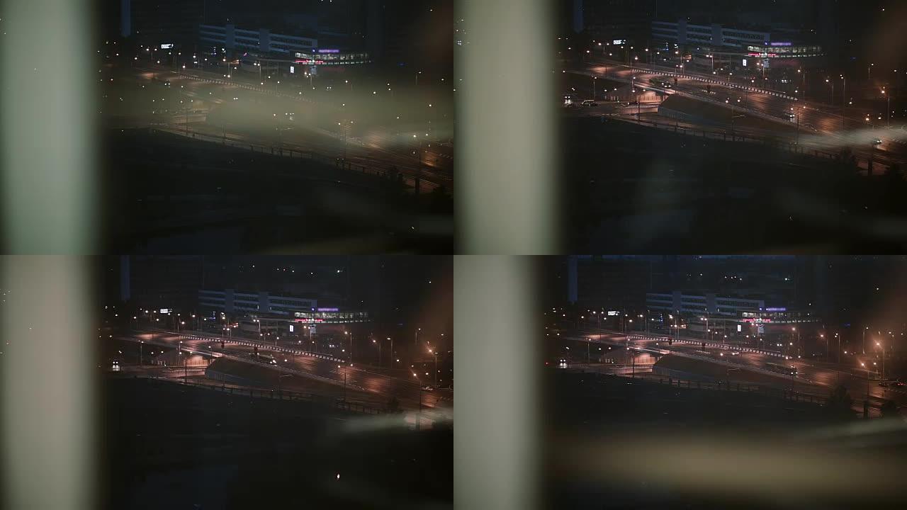 城市夜间有汽车的道路。从下降电梯的窗户看