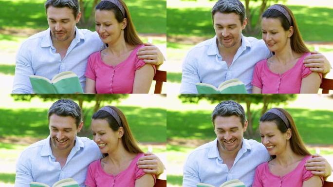 幸福的夫妇坐在公园的长凳上一起阅读