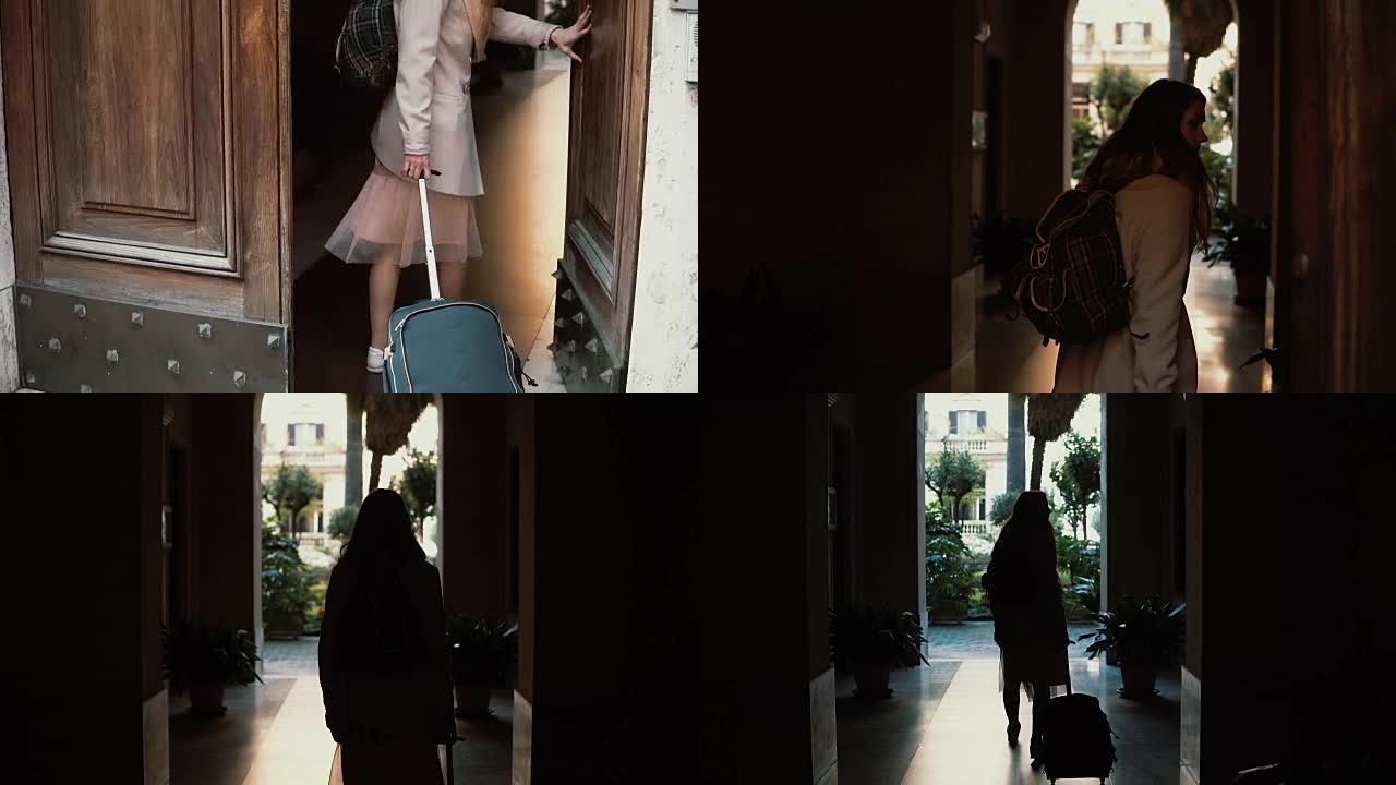 年轻的旅行者女人在街上带着手提箱散步。女孩打开门，走进拱门
