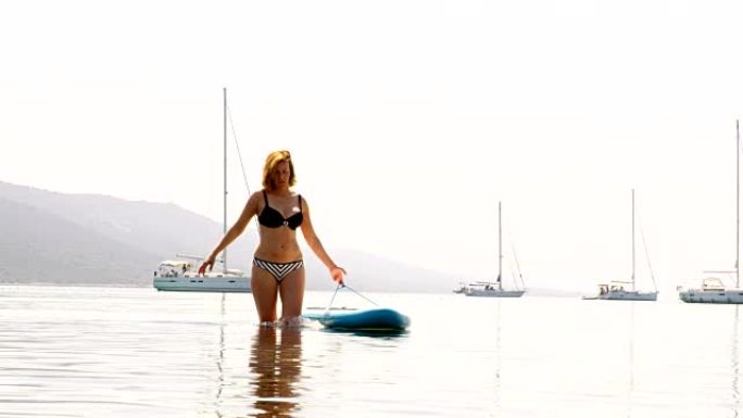 女人带着一块冲浪板走回海滩