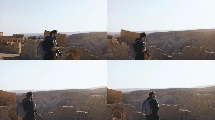 专业摄影师探索古代遗迹。山景附近有相机和背包的欧洲男子。以色列4K
