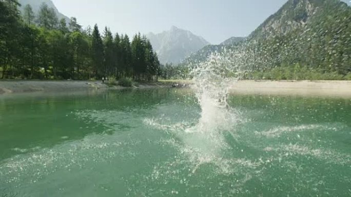 慢动作特写: 年轻的高加索女人在夏天美丽的晴天跳进水晶般清澈的山湖