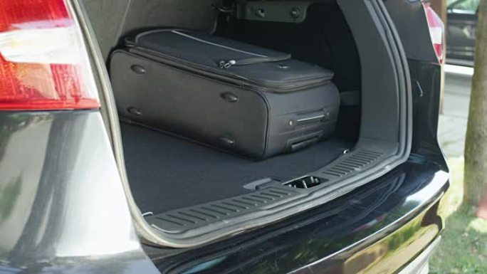 特写: 面目全非的人把旅行袋放在宽敞的汽车后备箱里。