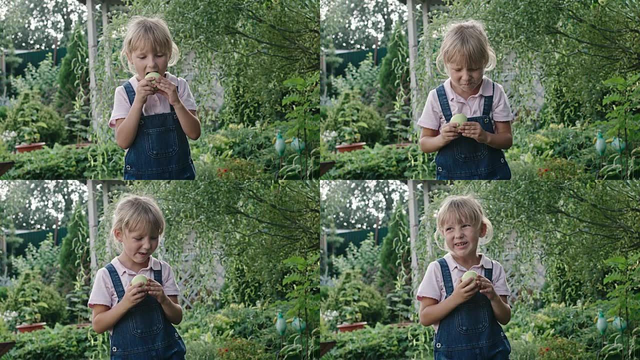 在绿色花园里吃酸苹果的女孩