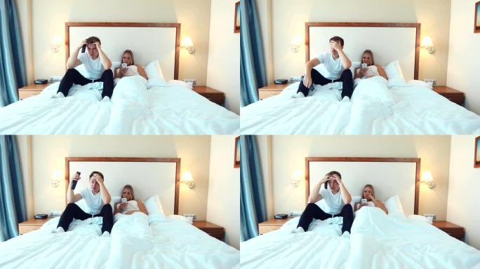 幸福的夫妻躺在床上看电视并使用智能手机