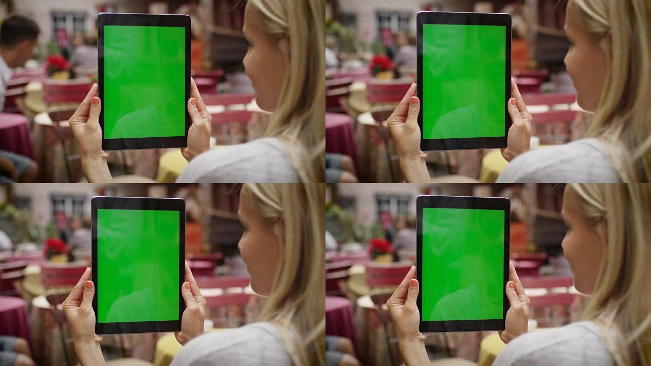 女孩在户外咖啡店以肖像模式拿着平板电脑