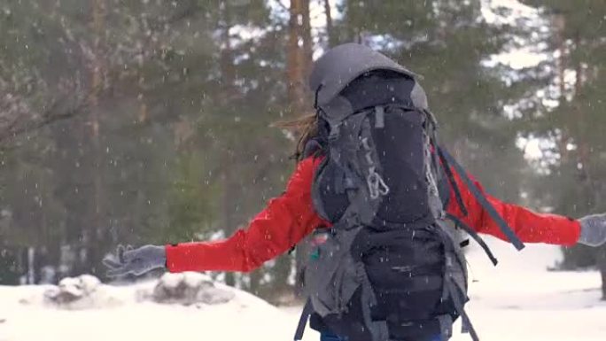 女孩在大雪下转身。旅行者，冬日森林中的徒步旅行者正面肖像。徒步旅行，爱情，纯洁，自由的概念。