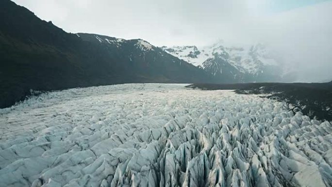 带灰烬的瓦特纳冰河冰川的美丽空中全景。直升机飞越冰岛国家公园的冰山