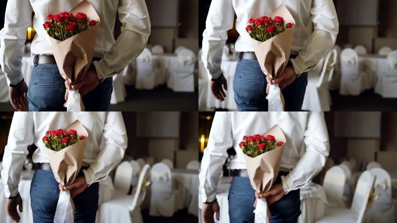 有爱心的人将红玫瑰藏在他的背后，为他在餐厅的约会带来美丽的花束。鲜花、浪漫关系和约会概念。