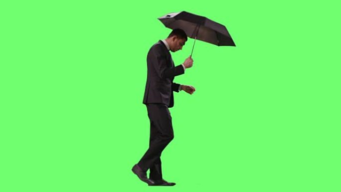 西装商人边走边撑伞。在模拟绿色屏幕上拍摄。
