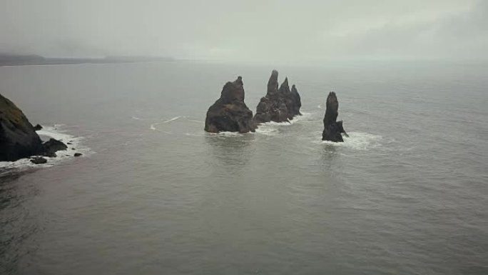 冰岛水中巨魔脚趾山的鸟瞰图。多雾的日子里，直升机在海上的悬崖上飞来飞去
