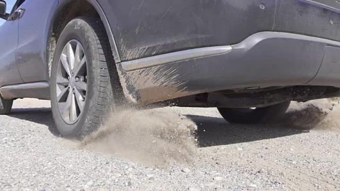 泥泞的SUV汽车快速开走，轮胎旋转快速扬沙扬尘