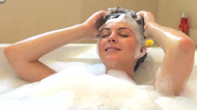 女人在充满泡沫的浴缸里洗头