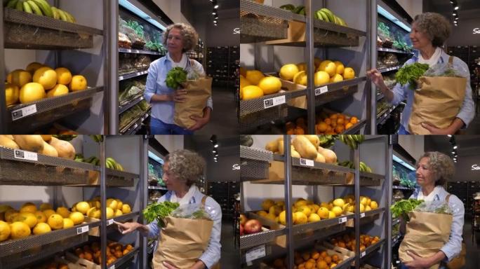 高级妇女在有机食品市场购物，看着货架上的食品价格并选择水果